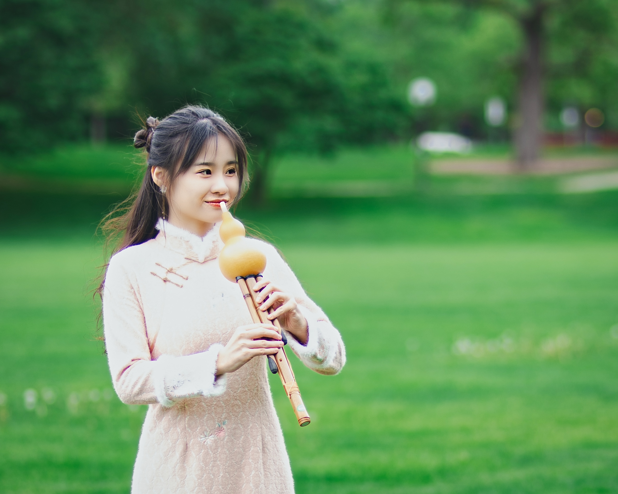 Young woman in a cheongsam playing the hulusi flute in a green park — Twin Cities event and senior portrait photography by Loon & Birch Photography