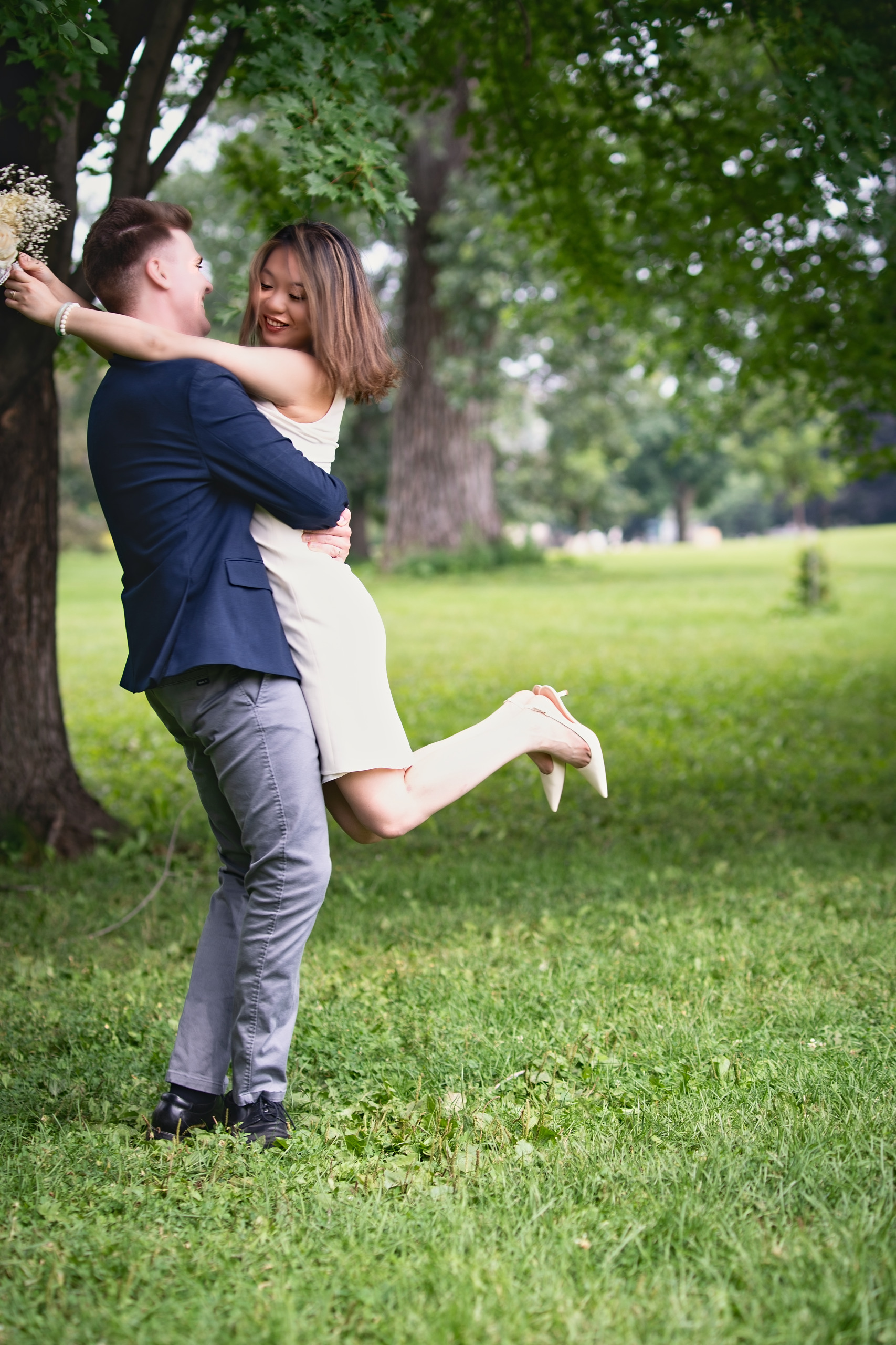 Groom lifting the laughing bride in a park after their wedding — Twin Cities wedding photography by Loon & Birch Photography