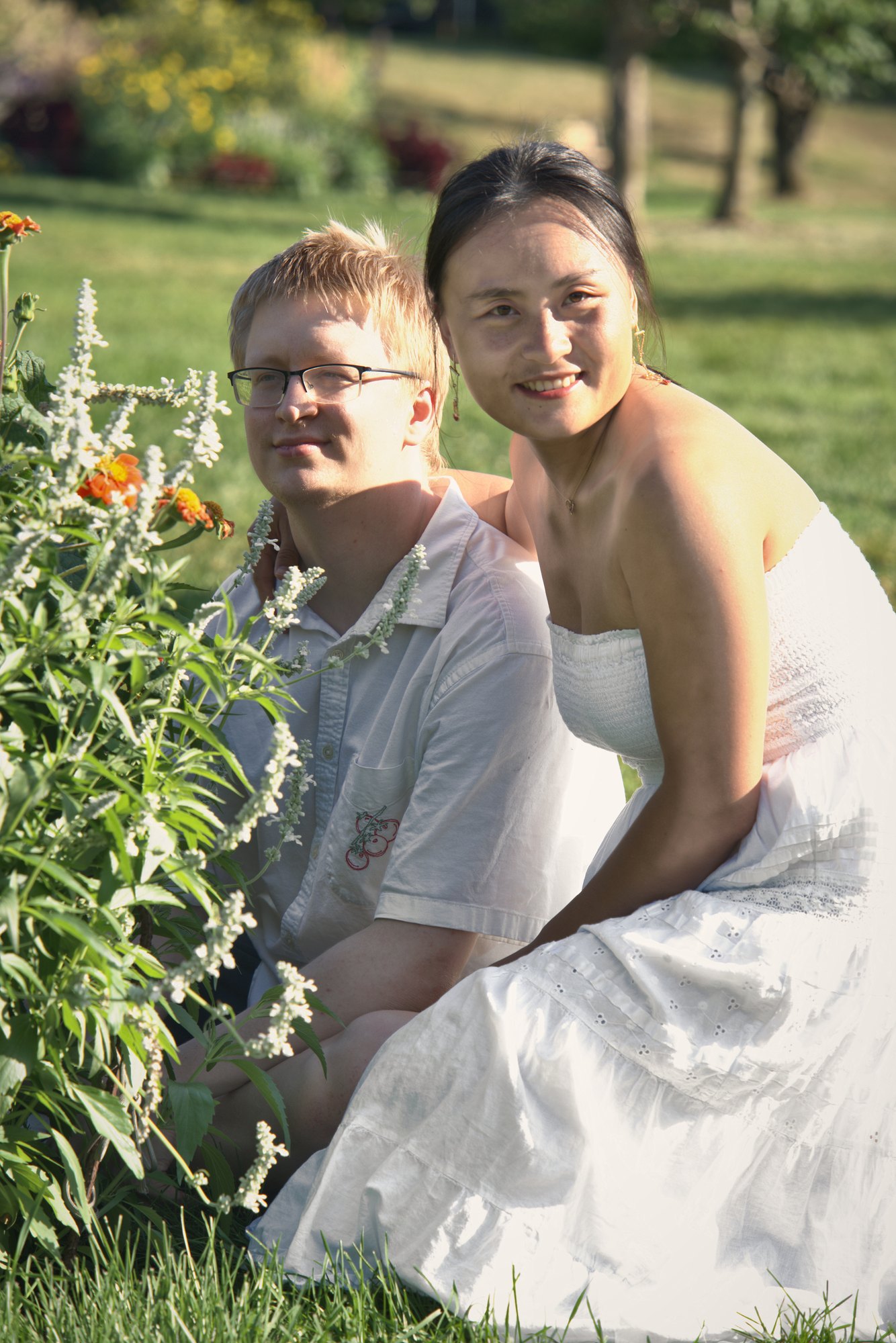 Smiling couple kneeling beside wildflowers in a Minnesota garden — Twin Cities couples and engagement photography by Loon & Birch Photography
