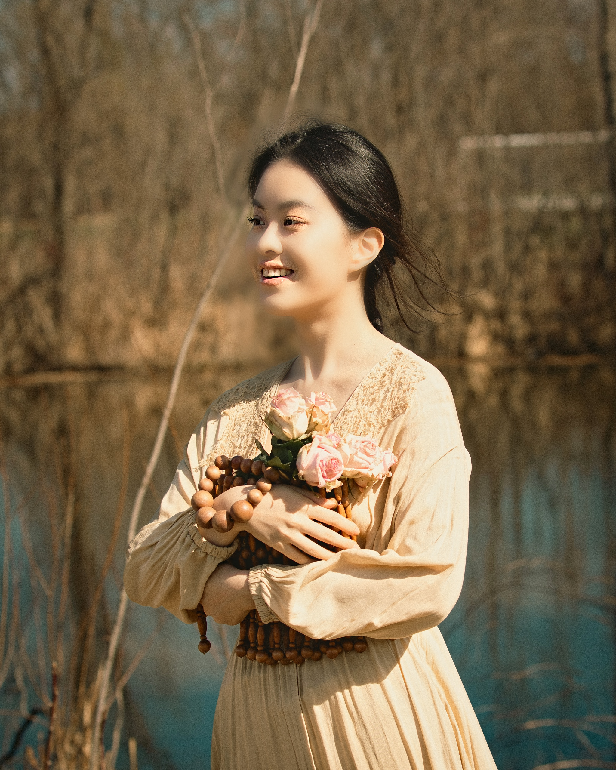 Young woman holding flowers in golden afternoon light by the water — Twin Cities event and senior portrait photography by Loon & Birch Photography
