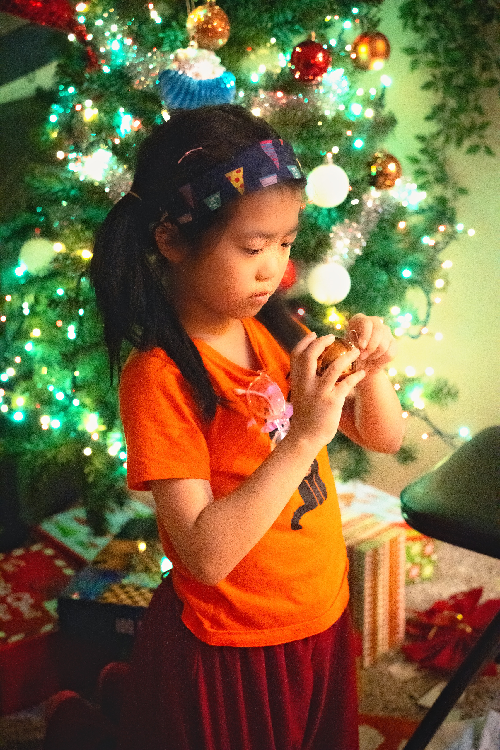 Child hanging an ornament on a glowing Christmas tree — Twin Cities family photography by Loon & Birch Photography