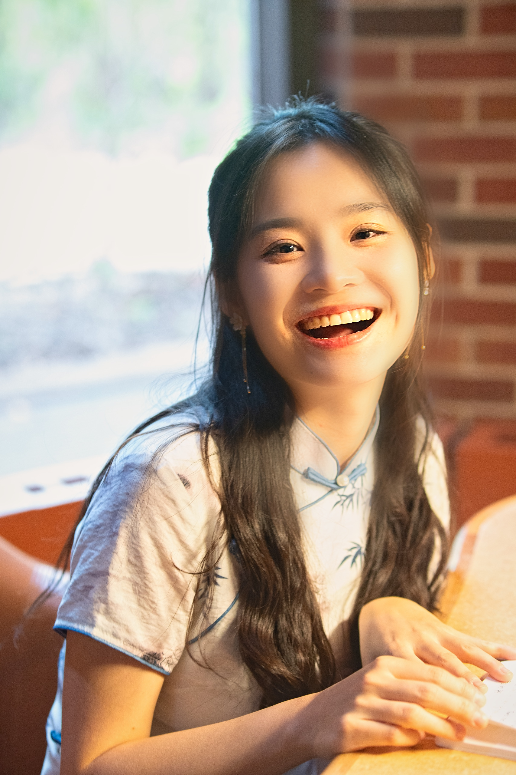 Young woman laughing against a warm brick wall — Twin Cities event and senior portrait photography by Loon & Birch Photography
