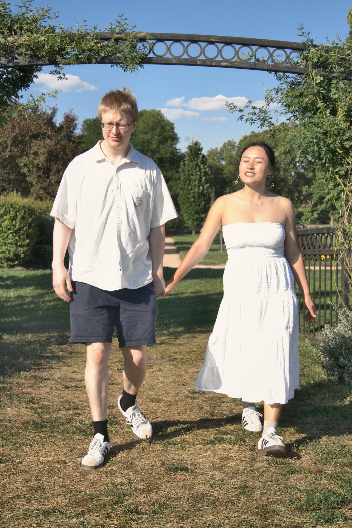 Couple walking hand in hand under a garden arch on a sunny afternoon — Twin Cities couples and engagement photography by Loon & Birch Photography