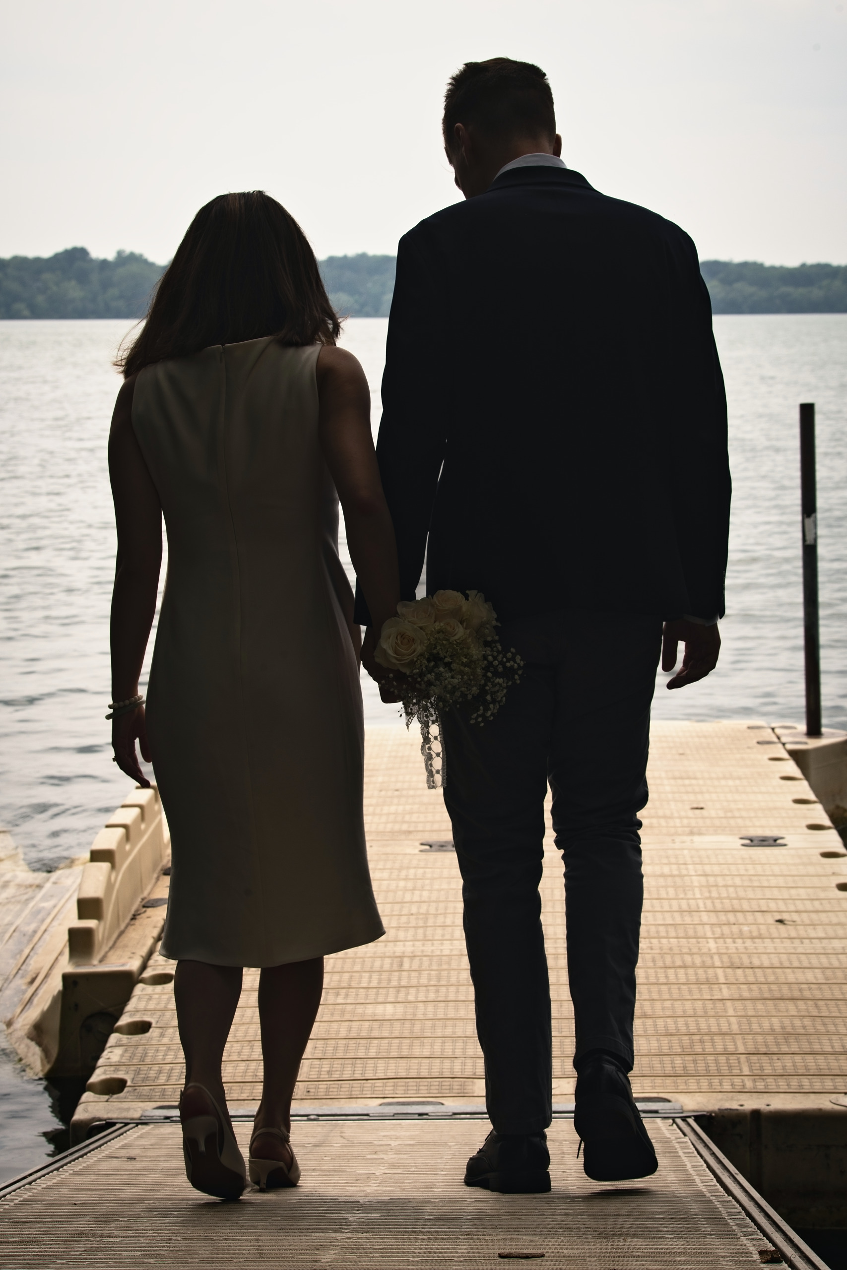 Bride and groom walking hand in hand along a Minnesota lake dock — Twin Cities wedding photography by Loon & Birch Photography