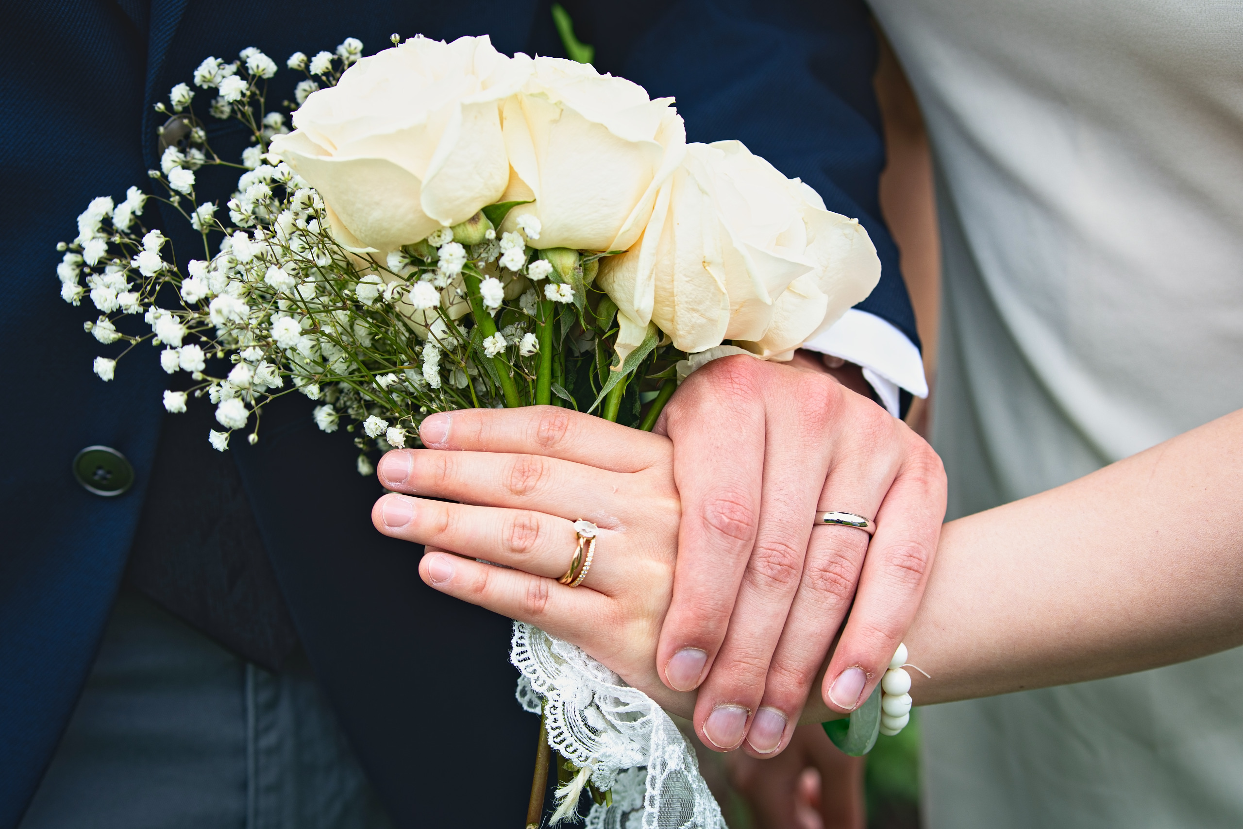 Bride and groom's hands with wedding rings resting on a white rose bouquet — Twin Cities wedding photography by Loon & Birch Photography